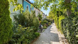 Green footpath with a child on a bicycle between terraced houses in Planegg