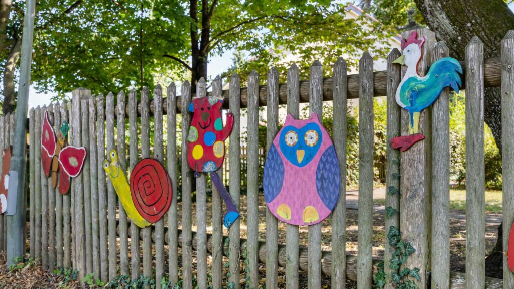 Wooden fence with colorful animal figures near a kindergarten in the area of Planegg house