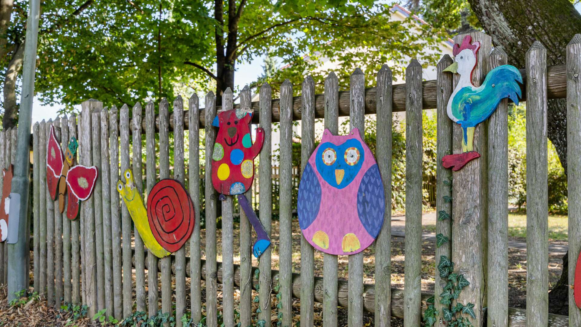 Wooden fence with colorful animal figures near a kindergarten in the area of Planegg house