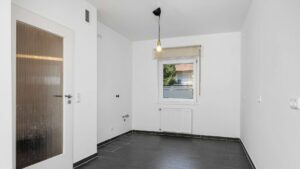 Empty room with dark tiled floor intended as a kitchen in the Planegg house