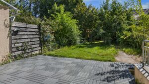 Paved patio with a view of the garden and wooden fence in the Planegg house