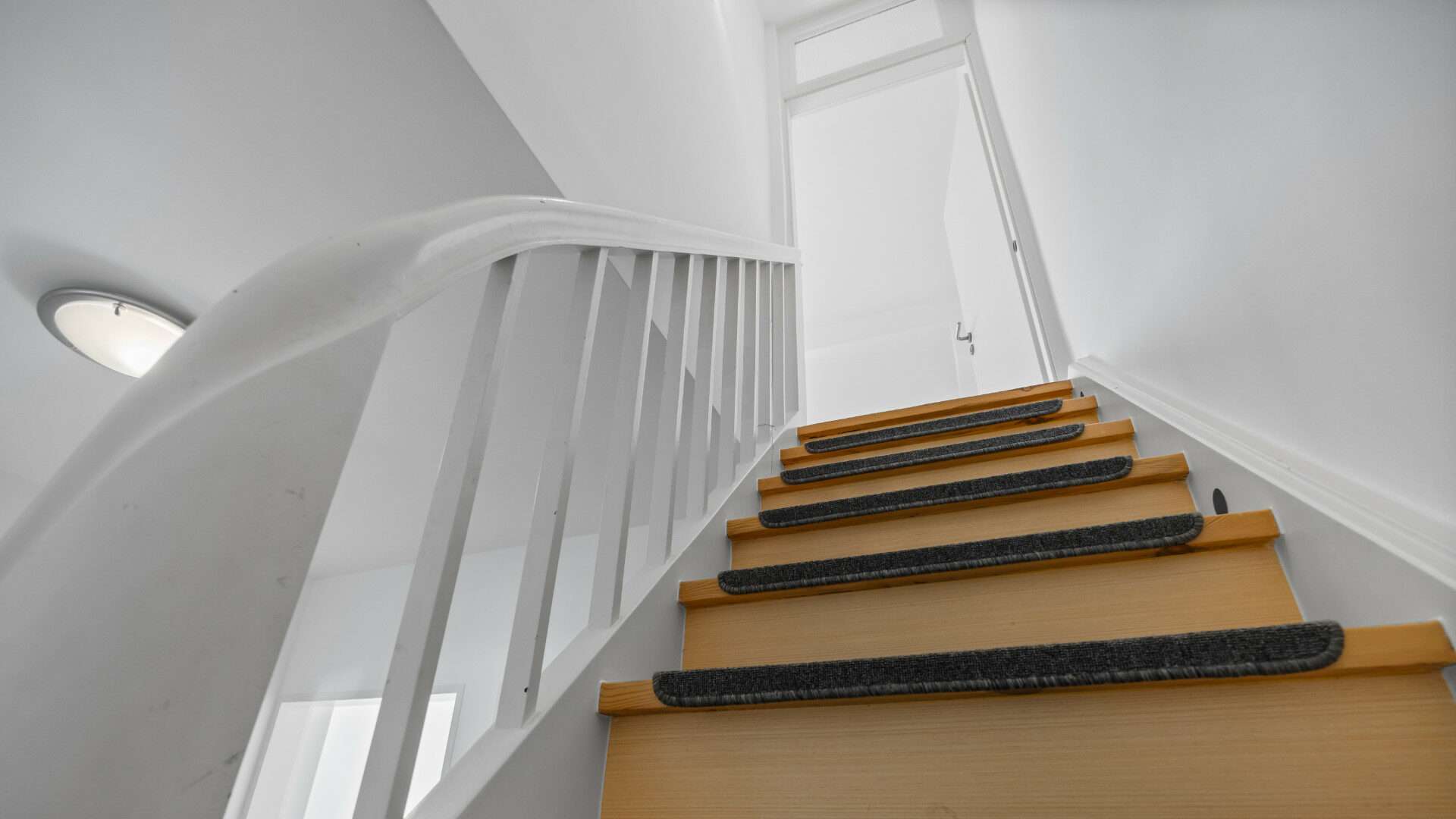 Curved white staircase with wooden steps in the Planegg house