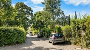 Quiet access road with hedges and parked cars in the residential area in Planegg