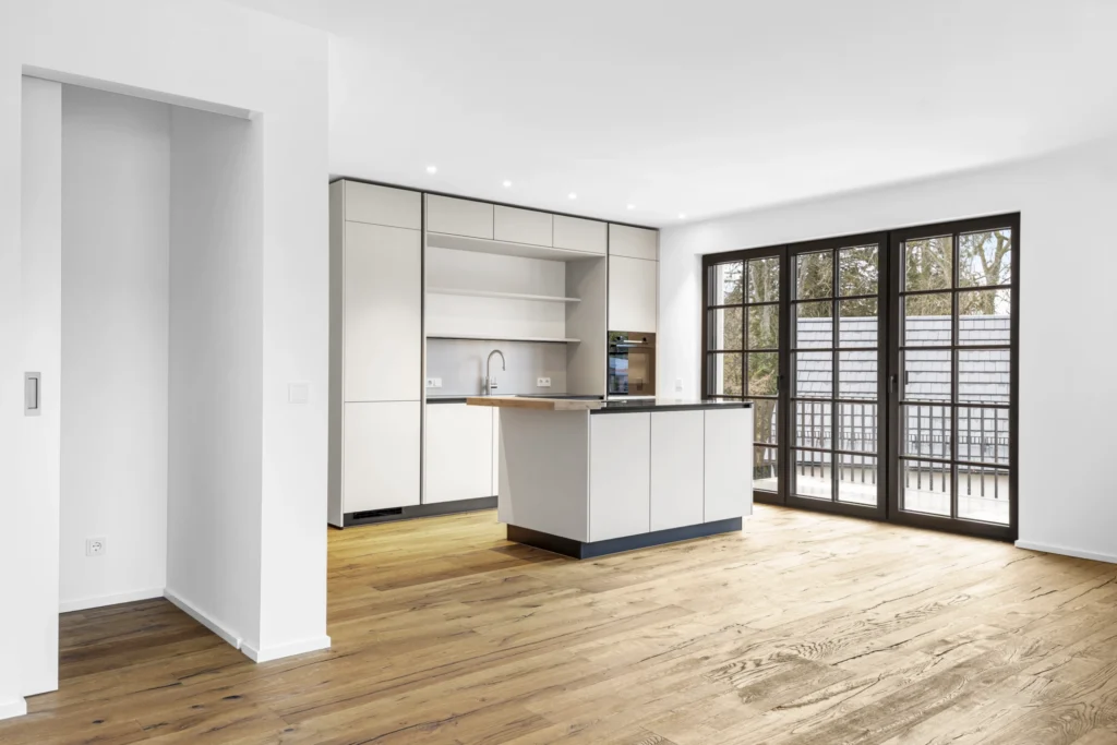 Open-plan kitchen-living room with kitchen island and patio door in rental apartment in Pöcking
