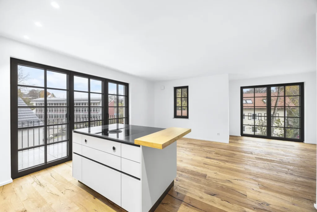 Open-plan kitchen-living room with kitchen island, hardwood floors, and balcony doors in a rental apartment in Pöcking