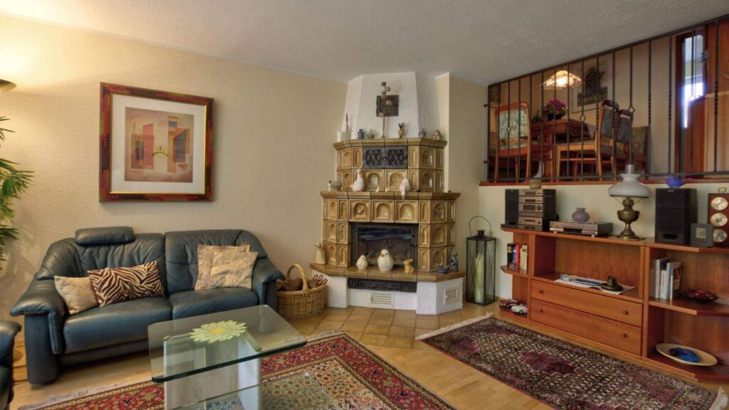 Living room with leather sofa and traditional tiled stove in a house in Puchheim