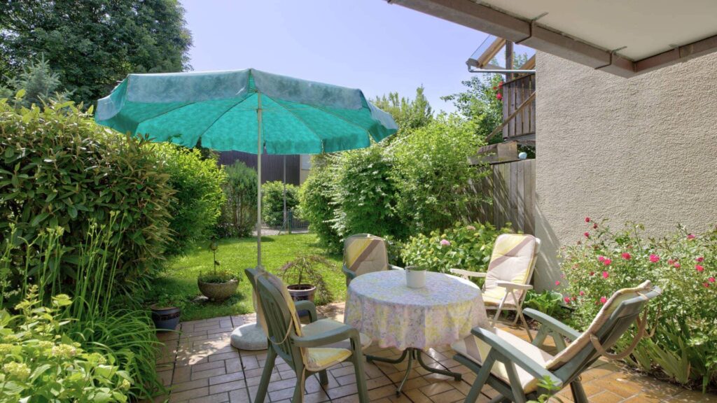 Terrace with sun umbrella and seating group in the garden of a house in Puchheim