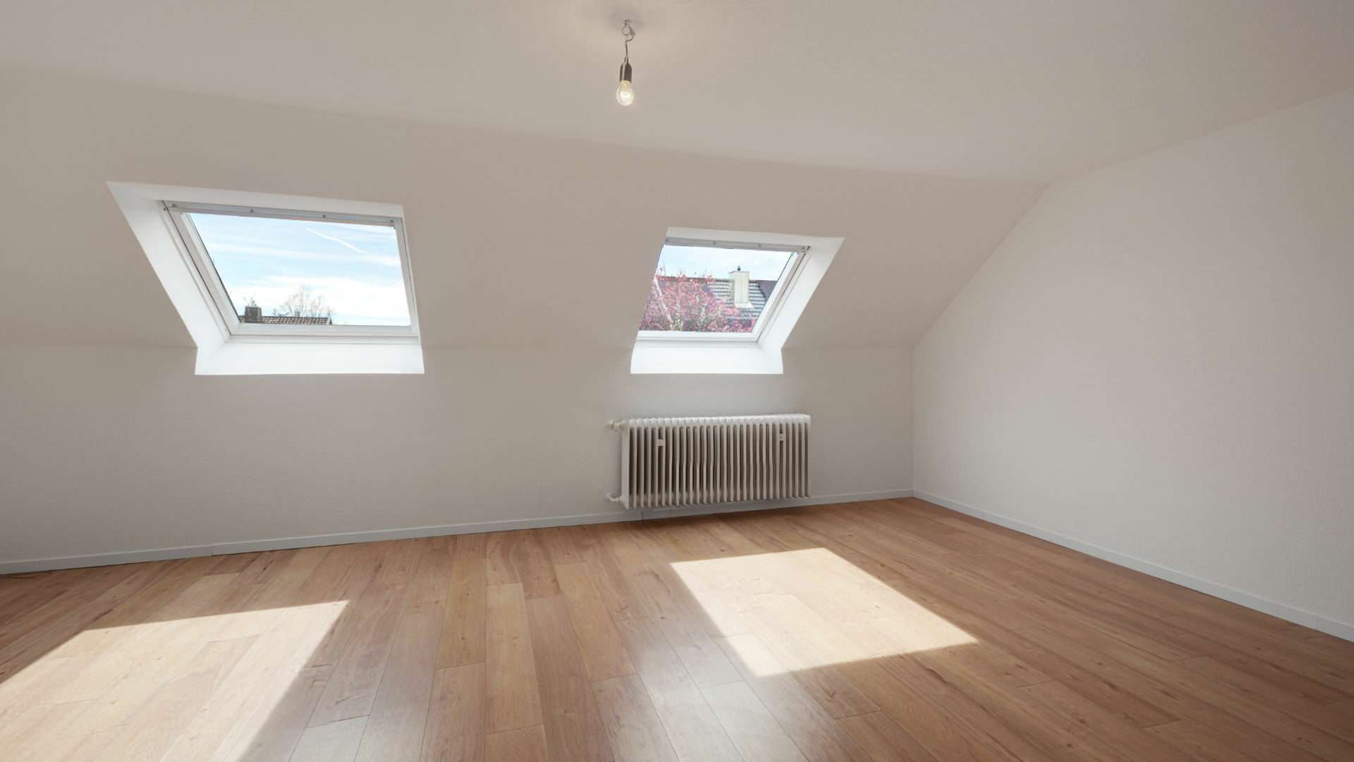 Empty attic room with two skylights and a wooden floor in the Putzbrunn house