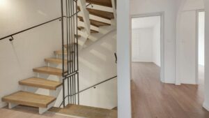 Wooden staircase with railing and view into the hallway with parquet flooring in the Putzbrunn house