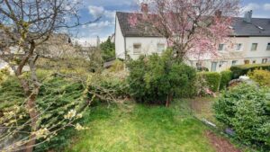 Garden with blooming tree and view of the row house development in Putzbrunn