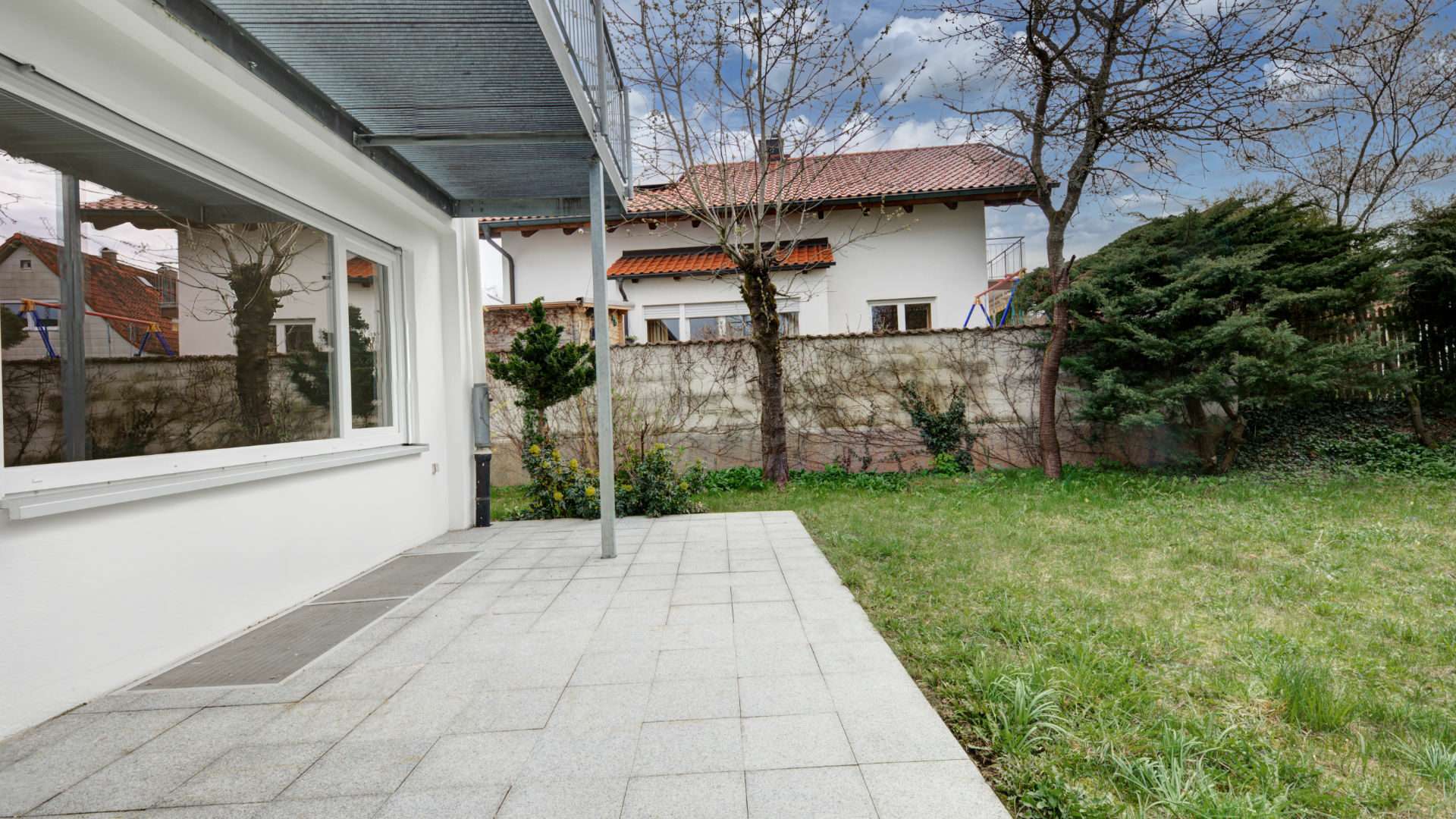 Covered terrace overlooking the lawn and neighboring house in Putzbrunn