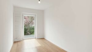Empty room with balcony door and view of a blossoming tree in the Putzbrunn house