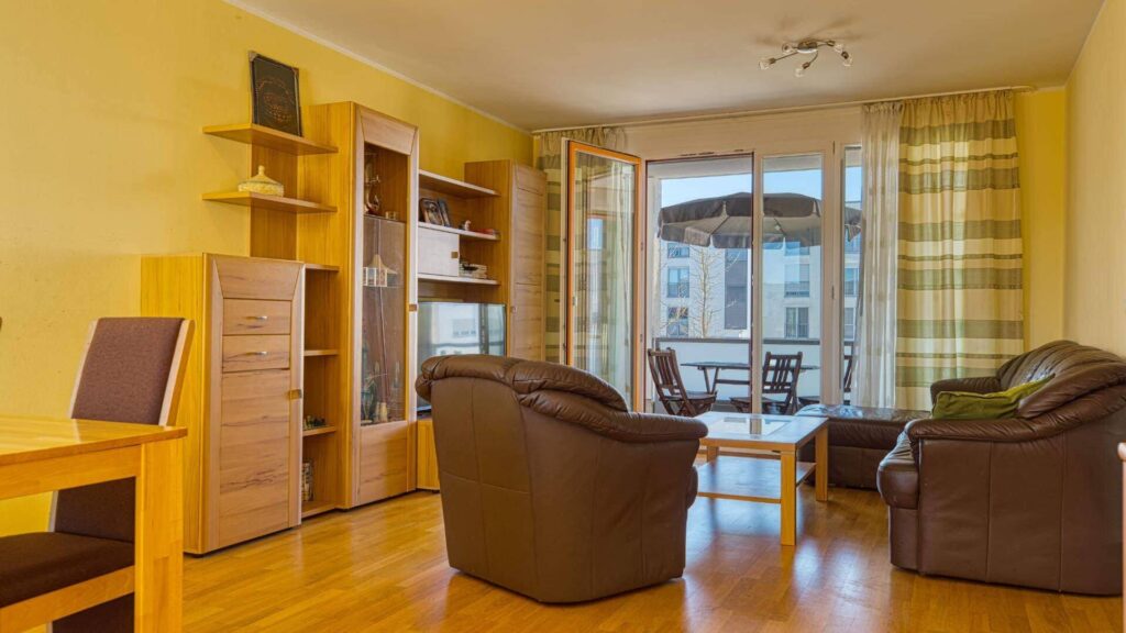 Wohnzimmer mit Ledersesseln und Balkonzugang in einer Wohnung in München-Riem