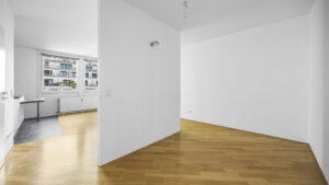 Leeres Zimmer mit Durchblick zur Küche und Parkettboden in einer Wohnung in München-Bogenhausen