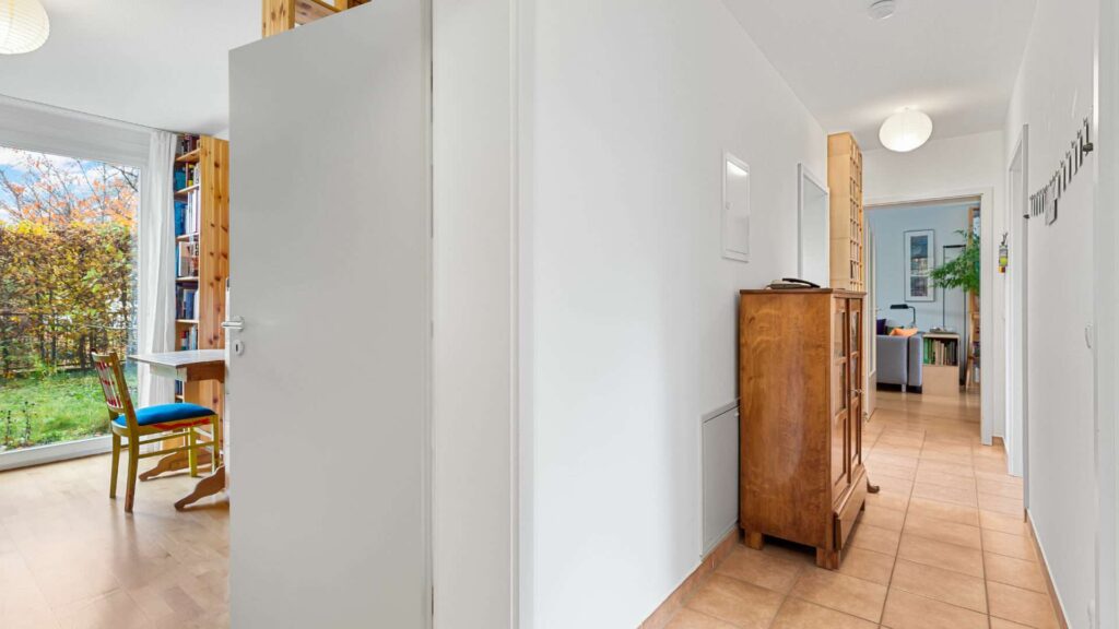 Hallway of the apartment in Munich-Schwabing with tiled floors and an antique wooden cabinet