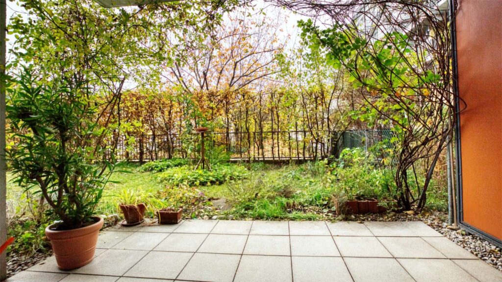 Terrace of the apartment in Munich-Schwabing with potted plants and a view of the autumn garden
