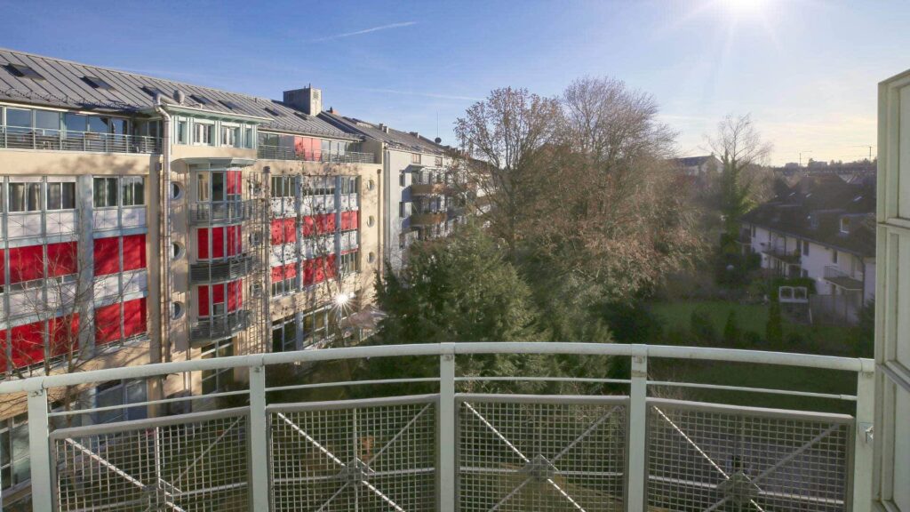 View from the balcony over residential buildings and a green area in Munich-Sendling