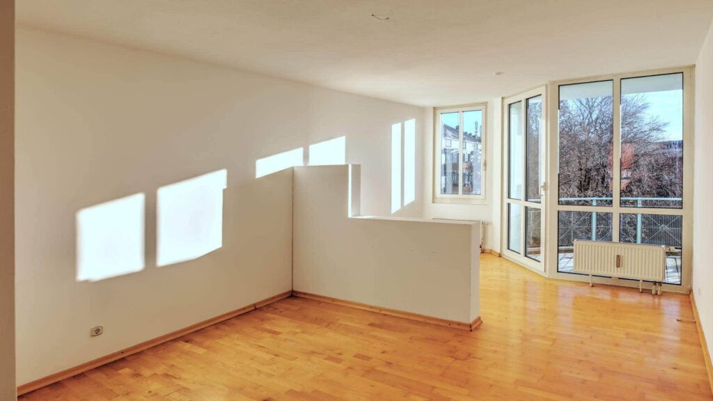 Empty living space with parquet floors and large windows in an apartment in Munich-Sendling