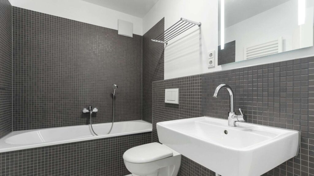 Badezimmer mit dunklen Fliesen, Badewanne und Waschbecken in einer Wohnung in Sendling