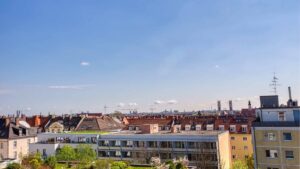 Blick vom Balkon über Dächer und Bäume der Wohnung in München-Sendling bei blauem Himmel