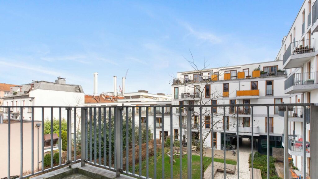 Blick vom Balkon auf einen begrünten Innenhof mit moderner Wohnbebauung in Sendling