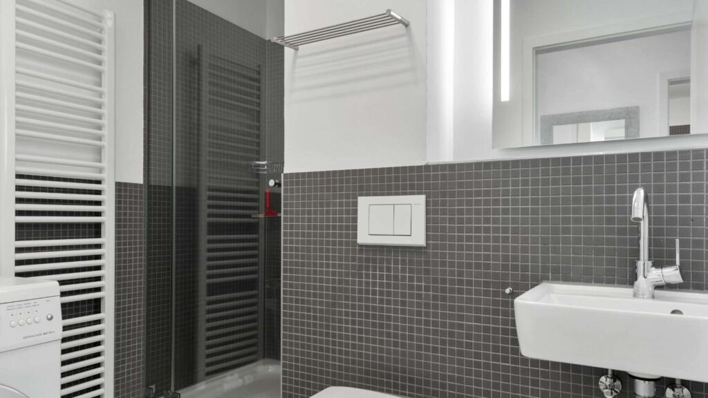 Gästebad mit Dusche und dunklen Fliesen in einer Wohnung in Sendling