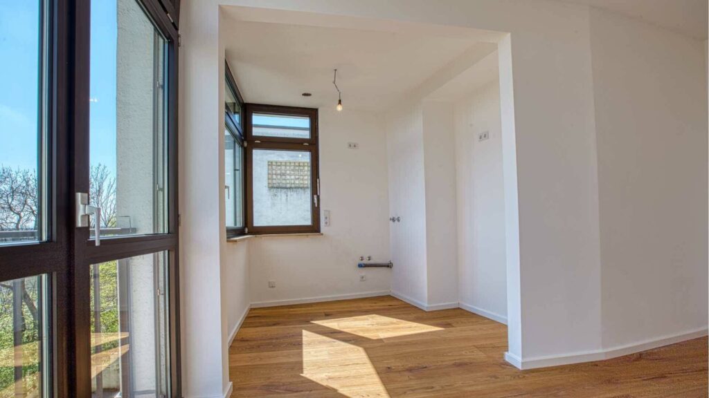 Leerer heller Raum mit Parkettboden und Fenster als Küchenbereich der Wohnung in München-Sendling