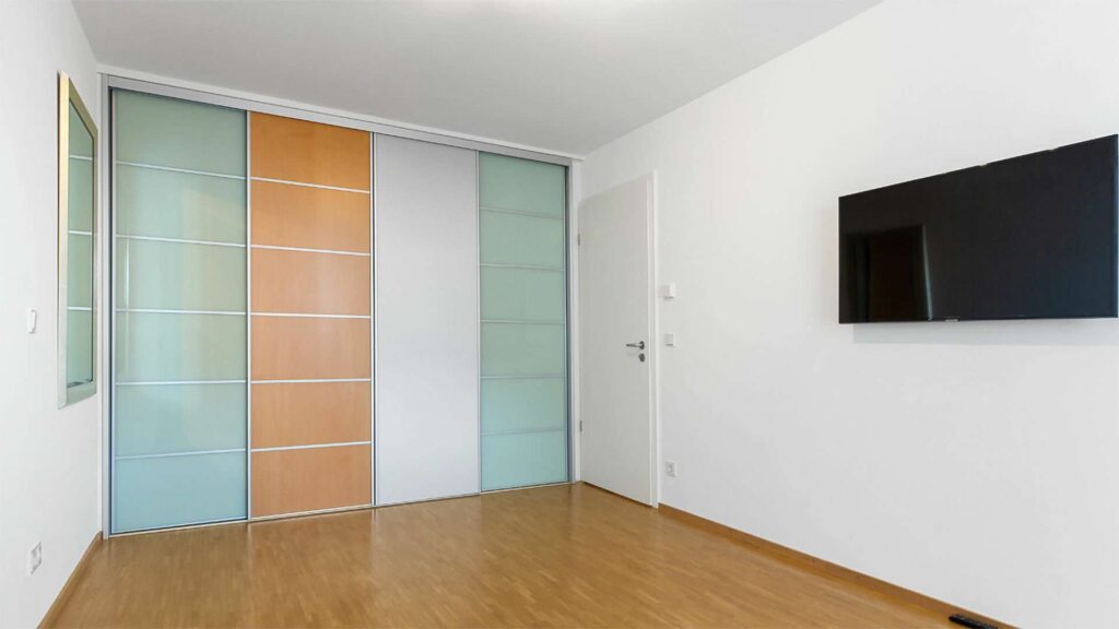 Schlafzimmer mit Einbauschrank und Parkettboden in einer Wohnung in Sendling