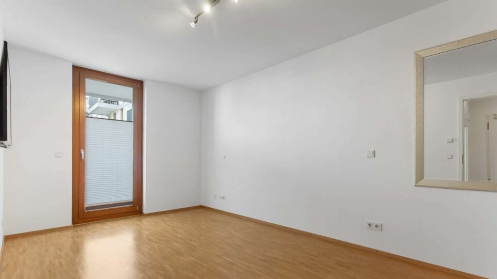 Leeres Schlafzimmer mit Wandspiegel und Parkettboden in einer Wohnung in Sendling