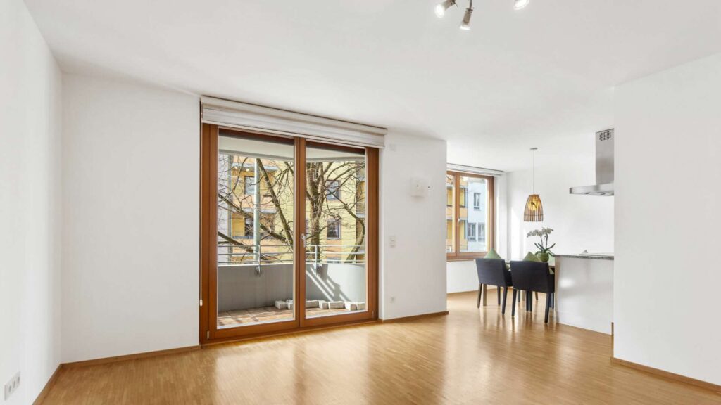 Wohn-Essbereich mit Balkonzugang und Blick in die offene Küche in einer Wohnung in Sendling