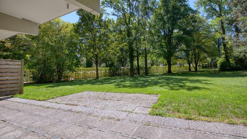 Terrasse der Wohnung in München-Solln mit Rasenfläche und Blick auf umliegende Bäume