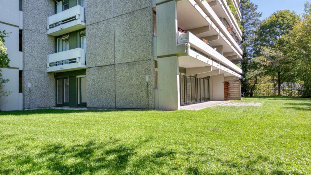 Außenansicht des Hochhauses in München-Solln mit Terrasse und Rasenfläche im Vordergrund