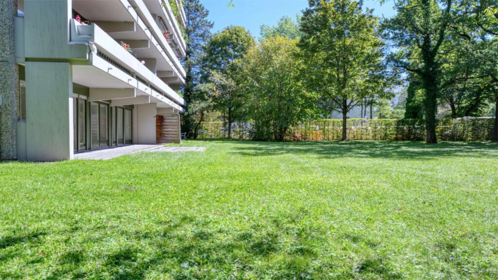 Terrasse der Wohnanlage in München-Solln mit Rasenfläche und Blick auf umliegende Bäume