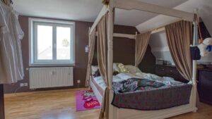 Bedroom with four-poster bed and sloping ceiling in the original condition of the apartment in Munich-Trudering