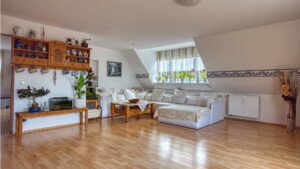 Spacious living room with seating area, parquet flooring, and sloped ceilings in the existing Trudering apartment