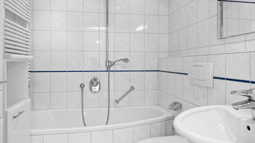 Tiled bathroom with bathtub, sink and blue trim in row house for rent Unterhaching