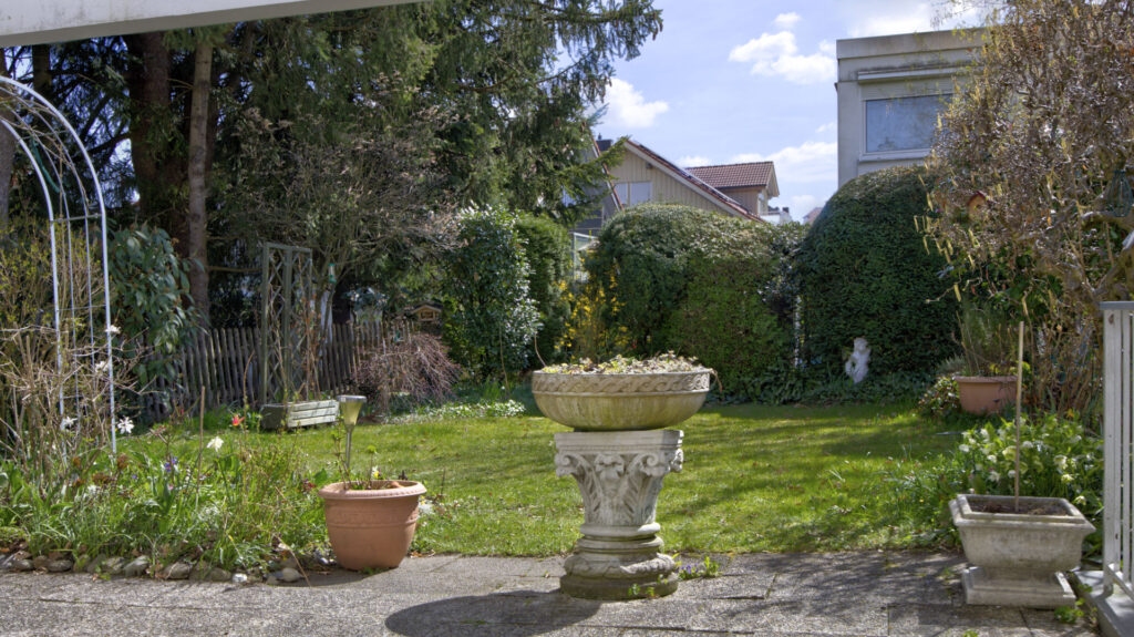 Well-kept garden with lawn area, stone fountain and planters at row-end house in Unterhaching near Munich