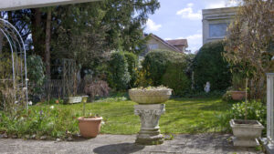 Gepflegter Garten mit Rasenfläche, Steinbrunnen und Pflanzkübeln bei Reihenendhaus in Unterhaching bei München