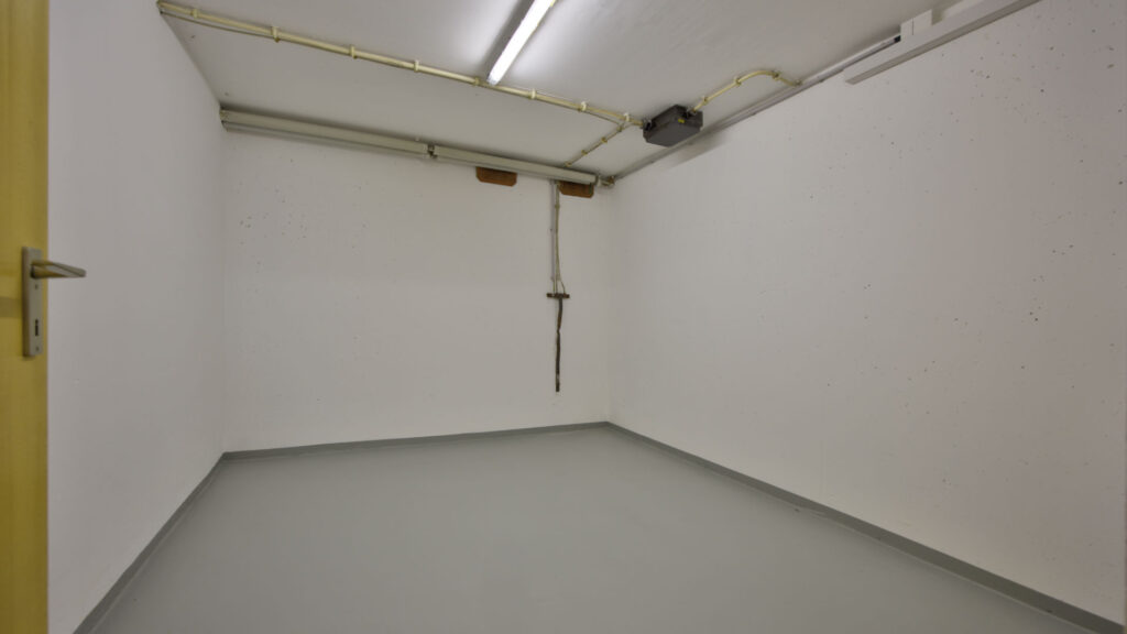 Empty white basement with yellow door and gray floor in Unterhaching