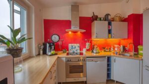 Einbauküche mit roter Rückwand und Elektrogeräten in einer Wohnung in Unterschleißheim