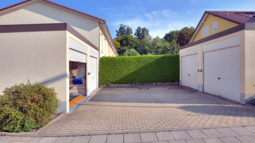 Two garage parking spaces with a paved driveway and a hedge at the townhouse in Germering – Rogers Real Estate