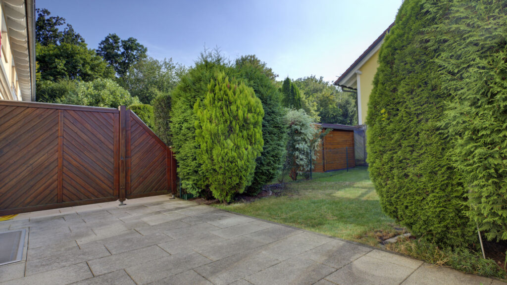 Paved patio with hedges and a garden shed in the garden of an apartment building in Germering