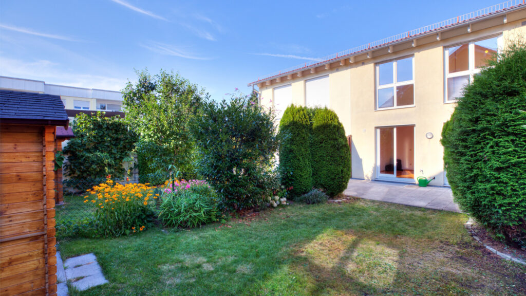 Garden view with patio and hedges behind an apartment building in Germering