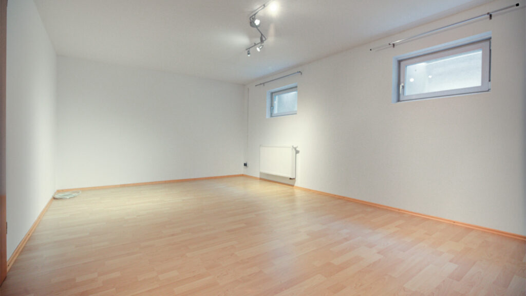 Empty, bright hobby room with wooden floors and small windows in a townhouse in Germering – Rogers Real Estate