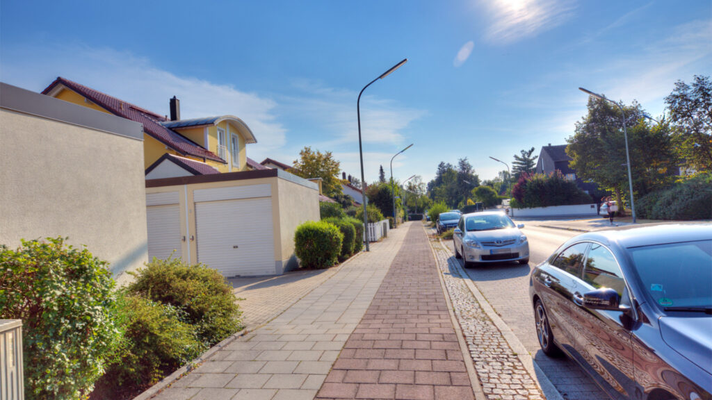A residential street with garages and single-family homes near an apartment building in Germering