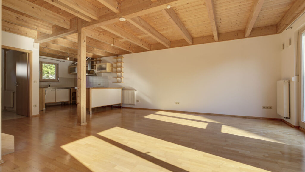 Living room with exposed timber beam ceiling and fitted kitchen in an apartment building in Germering