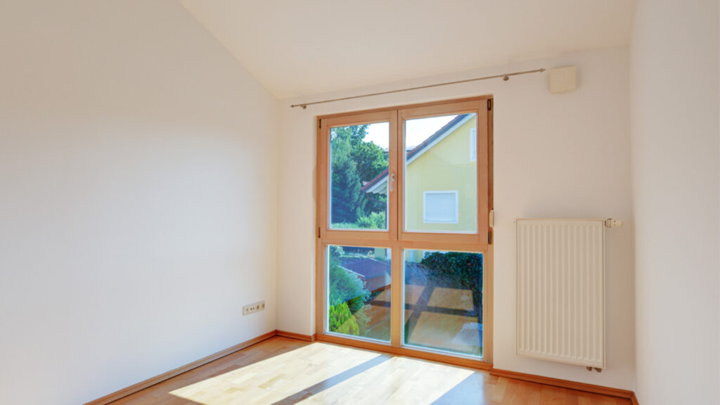 Empty room with patio door and parquet floor in an apartment building in Germering