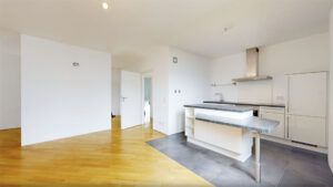 Leerer Wohnraum mit Blick auf die Einbauküche und Parkettboden in einer Wohnung in München-Bogenhausen