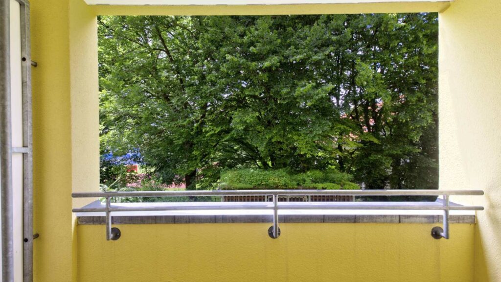 Blick vom Balkon der Wohnung in Berg am Laim auf Bäume und Metallgeländer