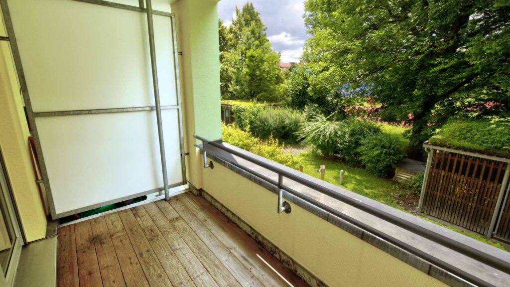 Balkon der Wohnung in Berg am Laim mit Holzboden, Geländer und Blick in den grünen Innenhof